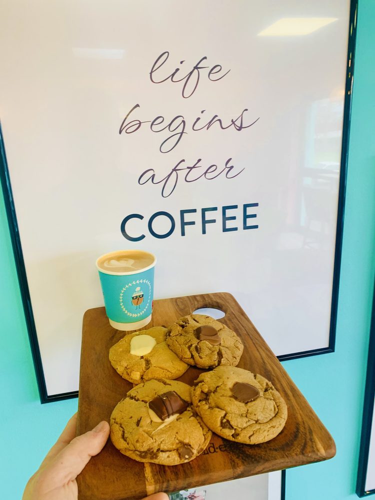 Cookies on a board held up beside a print reading life begins after coffee