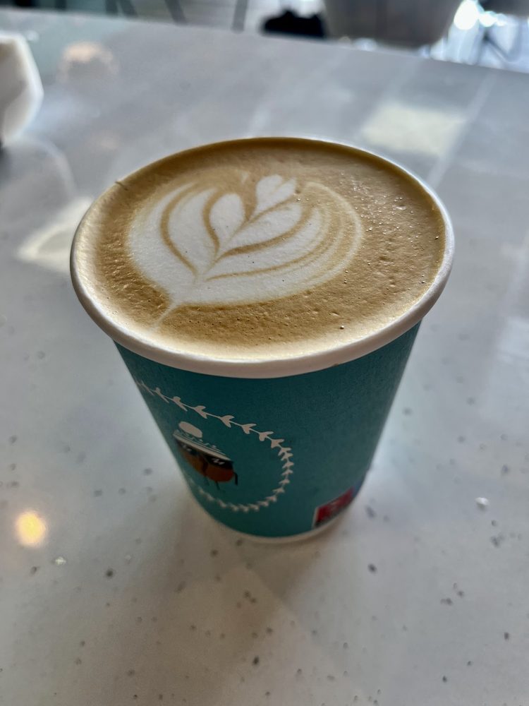 Latte art in a teal Chill the Beans cup