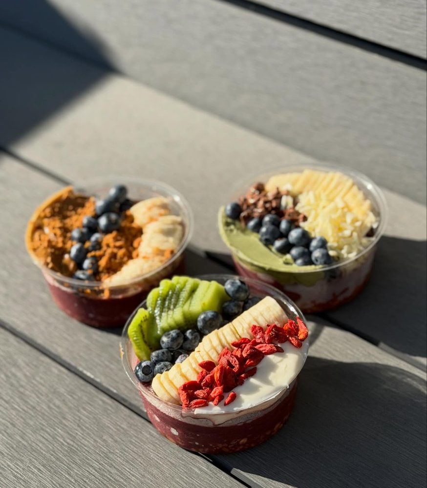 Three smoothie bowls topped with fruit, granola and coconut