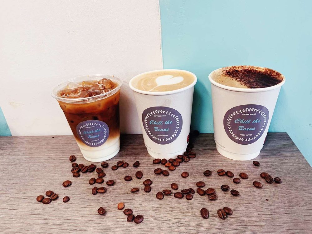Iced coffee, flat white and cappuccino with roasted beans scattered on the table