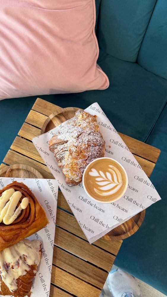 Almond croissant and latte art on a wooden board